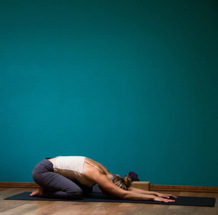 Yoga poses for mental health: A girl wearing white top performing yoga child pose