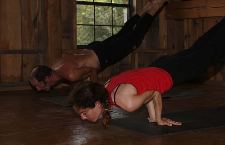 Couple performing yoga pose mayurasana at their house