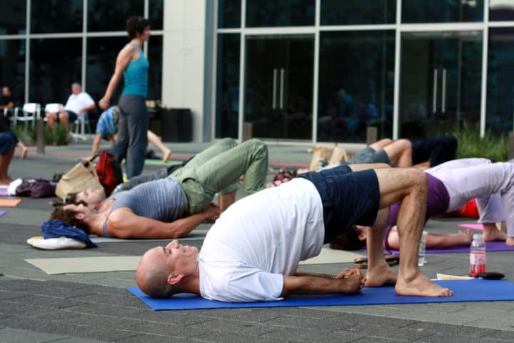 A group of some people practicing yoga bridge pose at a yoga center. Bridge pose helps relieve stress.